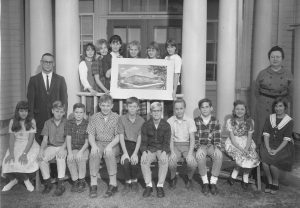These students in 1966 hold a rendering of the new school while standing on the steps of the old building, then used as a kindergarten.