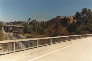 This photograph depicts the current road configuration in front of the rock. The 134 Freeway off-ramp is in the foreground. Figueroa Street runs to the dump road at left. In the middle distance is the 134 Freeway, which was constructed in 1970. The Edison Company power lines are carried on the monopoles, center. The rock and surrounding hills are at left. (ERVHS)