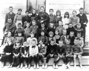 Eagle Rock’s Students in 1895. The teacher shown in the center of the back row was Miss Myra King, who taught through most of the 1890’s. Elena Frackelton is at her right. The trustees had added an open sided lunch area to the building. The first flag to fly over Eagle Rock flew here, it was hand sewn by Mrs. William Frackelton, Elena’s mother. (Courtesy the Elena Frackelton Murdock family, Photograph by C.C. Pierce)