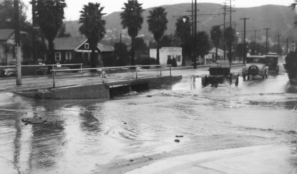 The railway track passes Yosemite Drive at Eagle Rock in the mid 1920’s. A heavy shower has flooded Yosemite Drive, the natural drainage from the rock stream. Bits of the then oiled roadway are floating in the stream. (LA Public Works Archive)