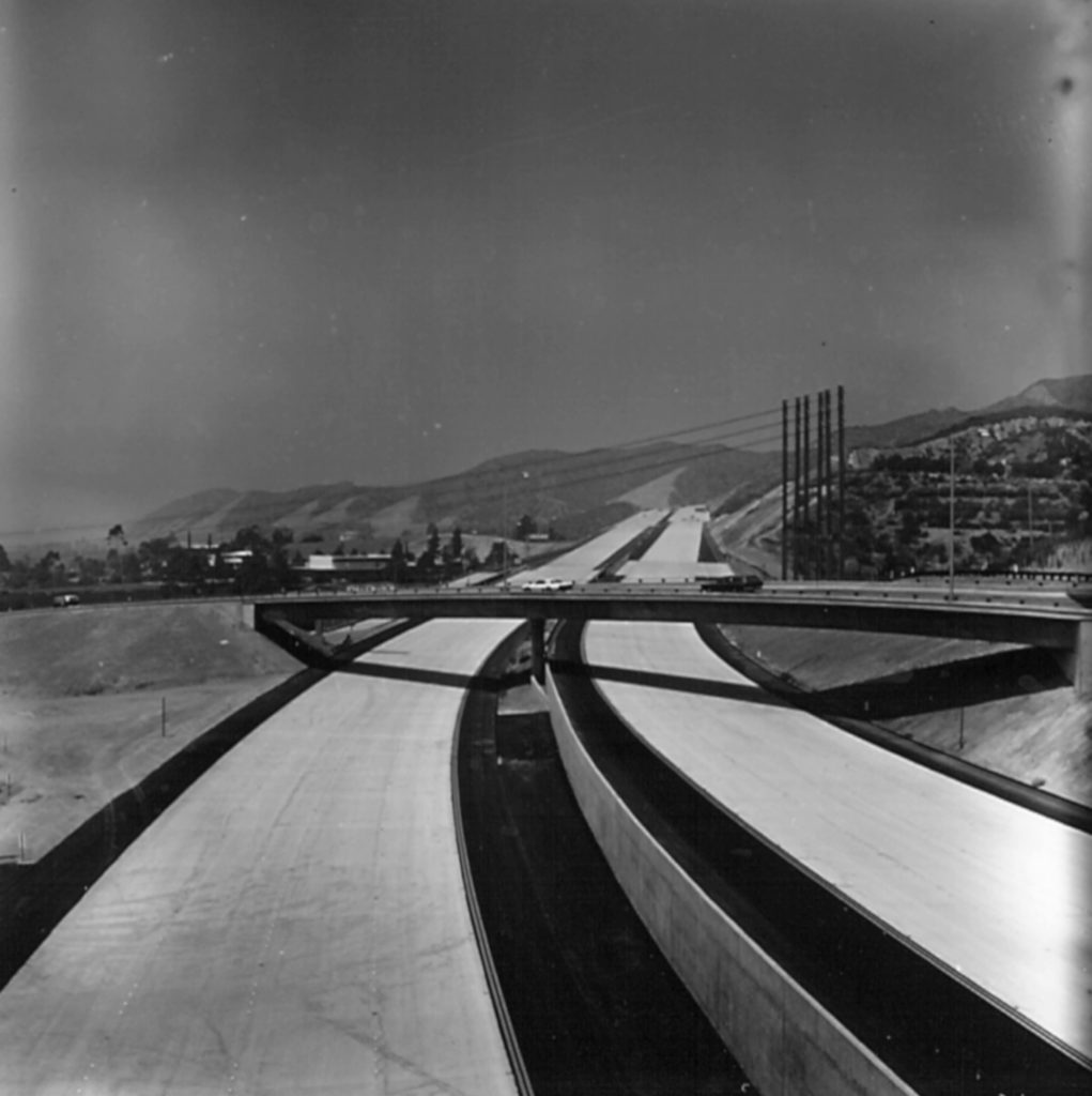 The brand new freeway proceeds under the existing off-ramp, past the monopoles carrying Edison’s high voltage lines, through the once wild hills above town. (Photo by Joe Friezer-Occidental college Library Special Collections Friezer Collection)